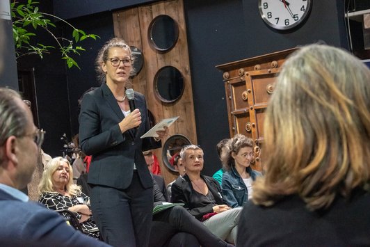 Teilnehmerin spricht zu den anderen Teilnehmern mit Mikrofon in der Hand