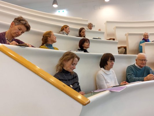 Menschen sitzen in einem Hörsaal der Uni Wien und hören sich die Studienpräsentation zur Bildungsforschung in Österreich an.