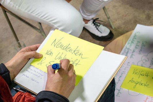 Teilnehmer schreibt auf ein Post-It: Neudenken von Unterricht und Schule