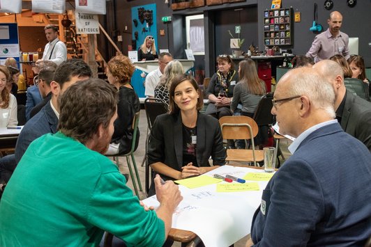 Teilnehmer sitzen als Gruppe an einem alten Schultisch und arbeiten zusammen