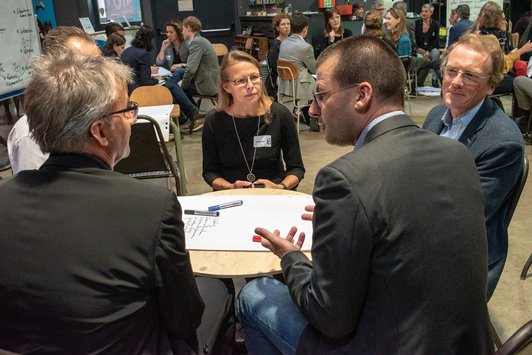 Teilnehmer sitzen als Gruppe auf einem alten Schultisch und arbeiten zusammen