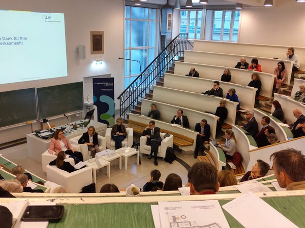 Menschen sitzen in einem Hörsaal der Uni Wien und hören sich die Studienpräsentation zur Bildungsforschung in Österreich an. 