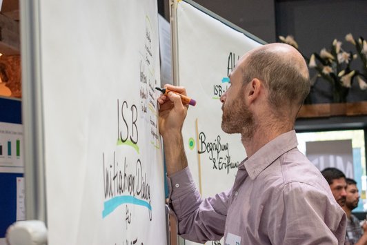 Der Moderator der Veranstaltung schreibt etwas auf das Flipchart